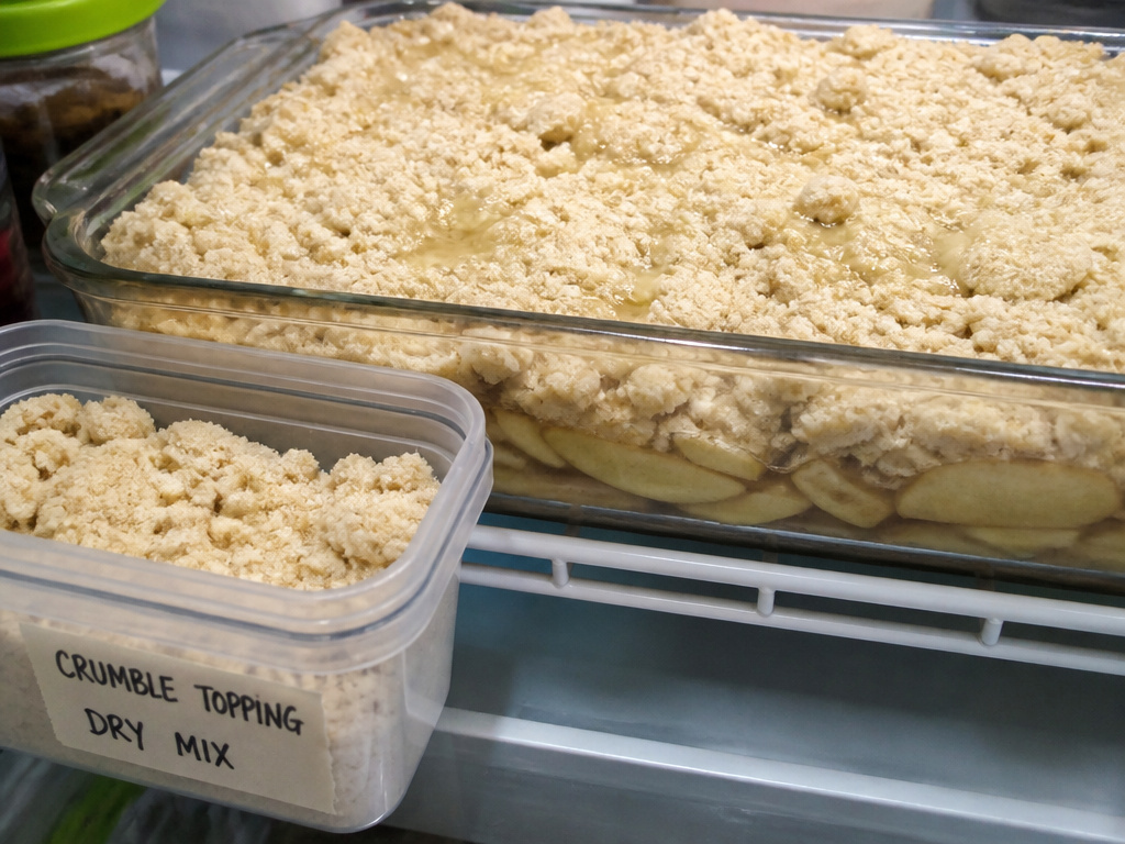 Raw apple crumble in fridge showing topping texture and separate airtight storage container.